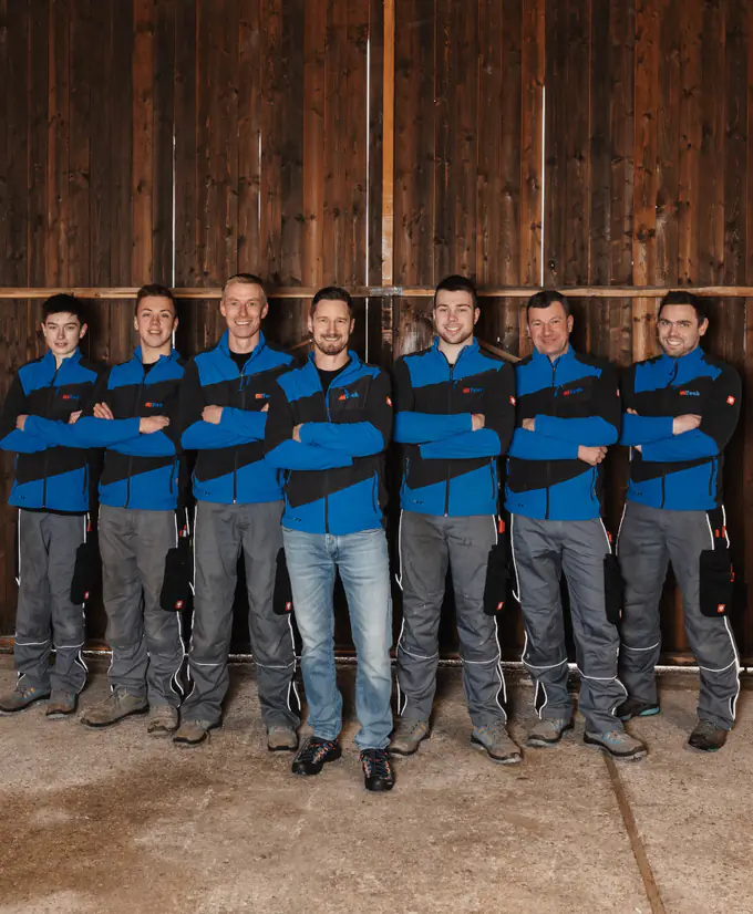 Das MiTech-Team vor einer Holzwand